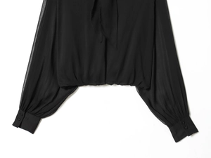 Detalle de blusa de gasa negra con cintura ajustada y puños de doble botonadura