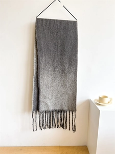 Detail of grey gradient scarf with soft tassel fringe hanging on a black hanger
