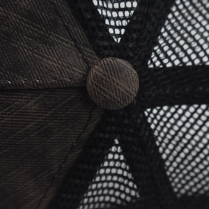 Macro shot of breathable black mesh and textured crown button on a classic trucker hat