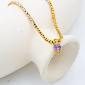 Detail of 18K gold-plated necklace featuring a purple zircon and white crystal accents