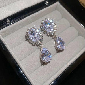 Macro view of sparkling teardrop zircon earrings on grey velvet jewelry box padding
