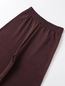 Detailed close-up of dark brown knitted pants featuring an elastic ribbed waistband texture