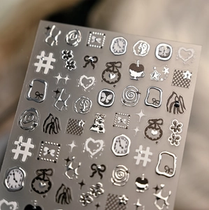 Macro shot of silver embossed nail stickers featuring clock and bow designs