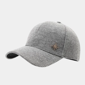 Detail of grey knitted baseball cap featuring a gold rhinestone star badge and soft wool texture