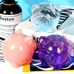 Detailed view of three cute pig ornaments in pink, purple, and glitter resin finishes
