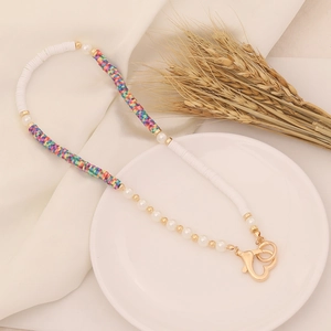 Detail of bohemian pearl and colorful polymer clay beaded necklace with gold heart clasp