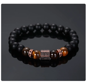 Macro detail of tiger eye beads and rose gold micro-pave cylinder on beaded bracelet