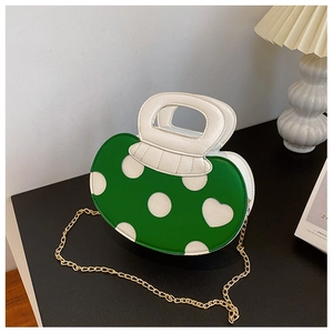 Detail of green and white heart polka dot handbag with gold chain strap on table