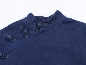 Detail of traditional Chinese knot frog button on dark blue denim cloak top fabric