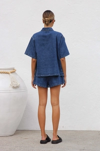 Rear view of loose-fit blue denim set showing fabric texture of short-sleeve shirt and shorts