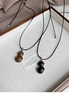 Detail of resin gourd pendant necklaces with leather inlay and silver frames