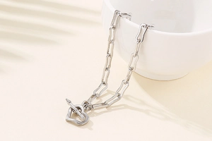 Close-up of silver stainless steel paperclip chain with heart charm and OT buckle
