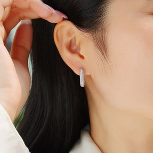 Close-up of silver hoop earrings with double-row pavé moissanite stones on earlobe
