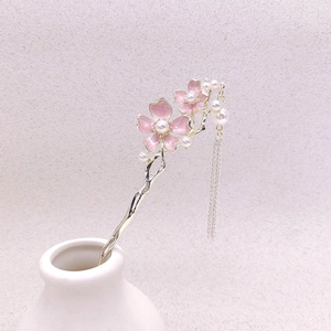 Pic à cheveux fleur rose élégant avec perles et pompons dans un vase blanc