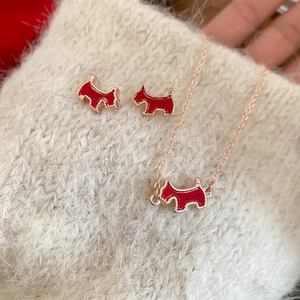 Detail shot of red enamel puppy necklace and stud earrings set on a cozy knit background