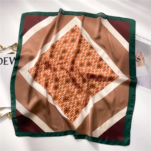Primer plano de pañuelo de seda con estampado de letra H y bloques de colores