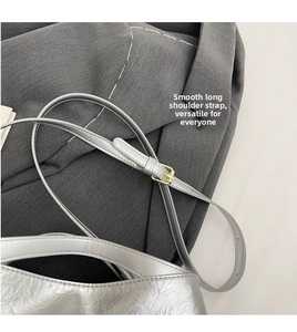 Detail of adjustable silver shoulder strap with light gold metal buckle and pleated texture