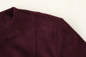 Close-up of shoulder stitching and soft suede texture on the dark burgundy jacket