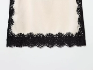 Détail de l'élégant tissu en satin crème avec bordure en dentelle de cils noire exquise