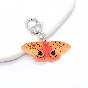 Macro shot of an orange acrylic butterfly keychain with fine black patterns and glitters