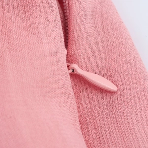 Macro shot of a hidden zipper on a pink woven midi dress with fine fabric texture