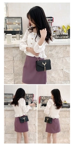 Detail of black crossbody bag with gold deer buckle and chain strap shown on model