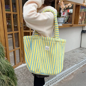 Gros plan sur le sac cabas en peluche rayé jaune et bleu au toucher doux