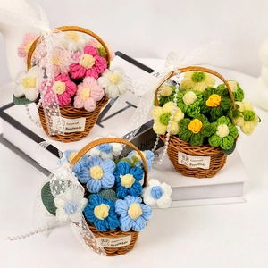 Three handmade knitted flower baskets with sunflowers and puff flowers on a desk