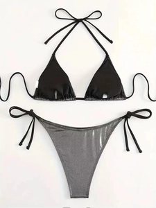 Dettaglio di paillettes sul top bikini nero e slip argento con lacci laterali