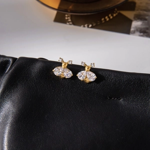 Golden bee stud earrings with zircon wings on a premium black leather surface
