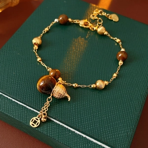 Detailansicht der Tigeraugen-Steine, Goldener Eichelanhänger und Münzelement am Armband