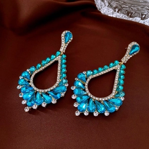 Close-up of vintage water-drop earrings with blue faceted crystals and pavé rhinestones