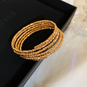 Macro shot of 5-layer gold plated bracelet with diamond-cut texture on black jewelry box