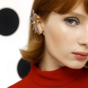 Macro detail of two-tone gold and silver leaf-shaped ear cuff on a female model