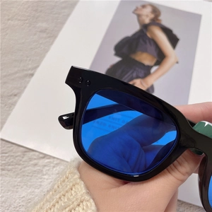 Detail shot of stylish black thick frame sunglasses featuring transparent blue tinted lenses