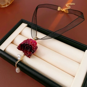Detail eines Vintage-Lace-Chokers mit roter Rosen-Applikation und Barockperlen