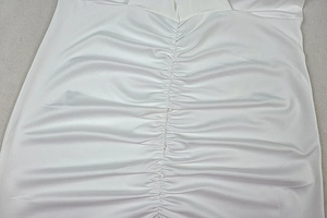 Detail of gathered stitching on a white long sleeve bodycon dress with elastic fabric