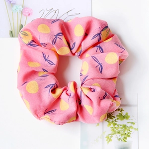 Close-up of pink fabric scrunchie with yellow lemon and blue leaf patterns