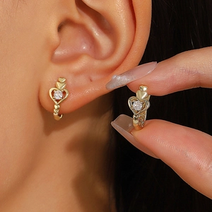 Detail of gold heart earrings with micro-set zircon and hollow interconnected heart design