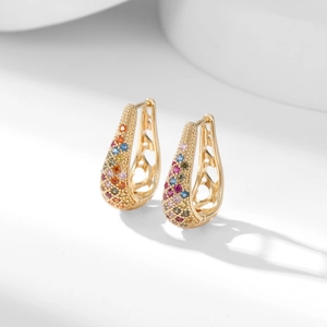 Macro detail of gold-tone huggie hoop earrings with multicolor rhinestones and heart cutouts