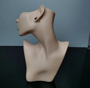 Detail view of a black geometric triangle stud earring on a neutral mannequin head display