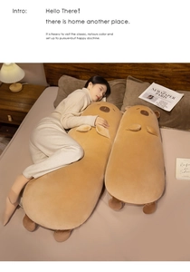 Detail of two long plush capybara pillows on a bed, showing soft brown fabric texture