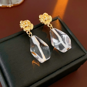 Close-up of golden rose earrings with irregular transparent resin floral pendants