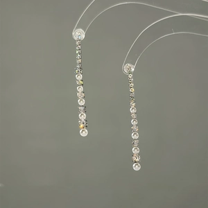 Close-up of silver long tassel earrings with sparkling rhinestones and round pearls
