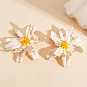 Detail of white acrylic flower earrings with yellow beaded stamens and a glossy finish