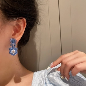 Detailed view of handmade Klein blue beaded flower earrings worn by a model