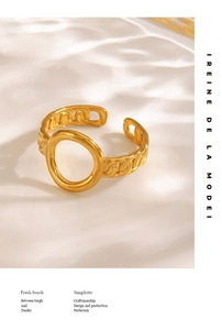 Detail shot of golden hollow oval ring with chunky chain band on textured white background