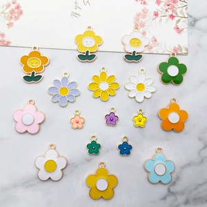 Colorful enamel alloy flower charms set on white marble surface with floral card