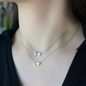 Detail of S925 silver and gold necklaces featuring letter C and heart pendants on a model