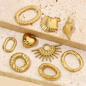 Golden geometric heart and shell shaped stainless steel charms on stone texture